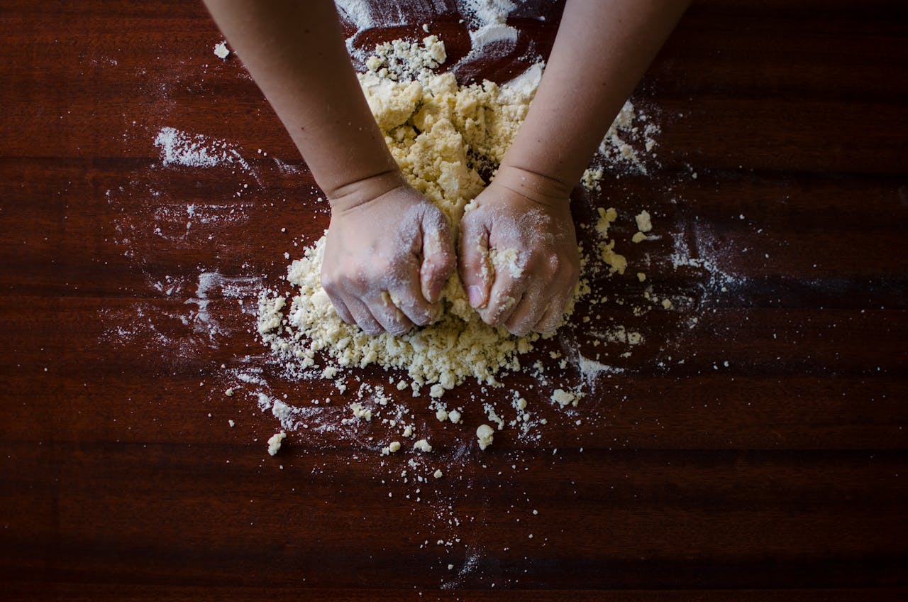 Close-up of hands kneading dough for baking on a wooden table, ideal for cooking themes.